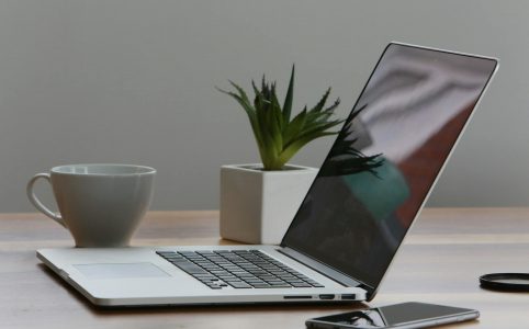 silver laptop and white cup on table