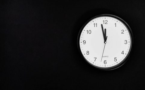 black round analog wall clock on black background